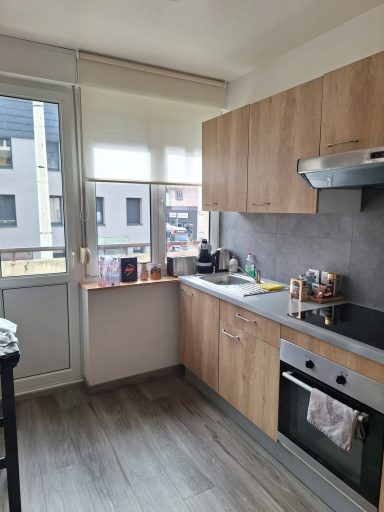 Cuisine moderne avec meubles en bois clair et équipements électroménagers.